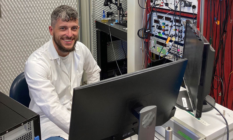 Ein Mann in einem Laborkittel sitzt an einem Computer.