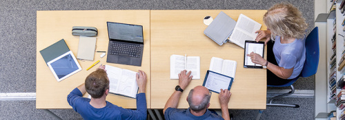 Drei Personen arbeiten an einem Tisch in der Bibliothek der FernUniversität