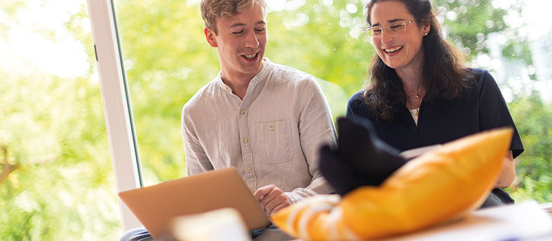 Bücher und Stifte am Arbeitsplatz mit einem arbeitenden Studierenden