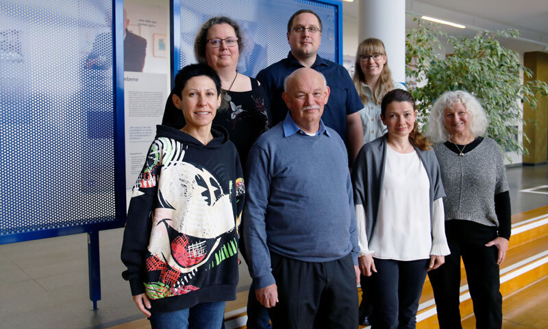 Fünf Frauen und zwei Männer stehen gemeinsam im Foyer der FernUniversität