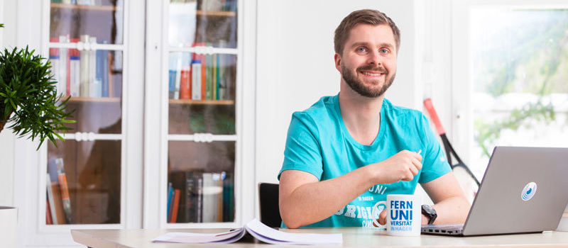 Student sitzt am Schreibtisch vor einem Laptop.