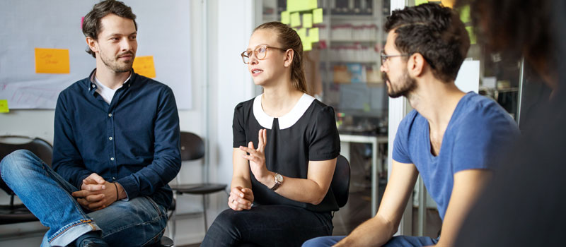 Gruppe von Menschen sitzt in Besprechung und diskutiert angeregt