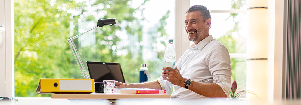 Mann sitzt mit Laptop am Schreibtisch