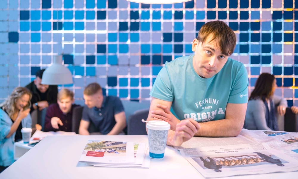 Studierender am Stehpult mit Zeitung und Zetschriften