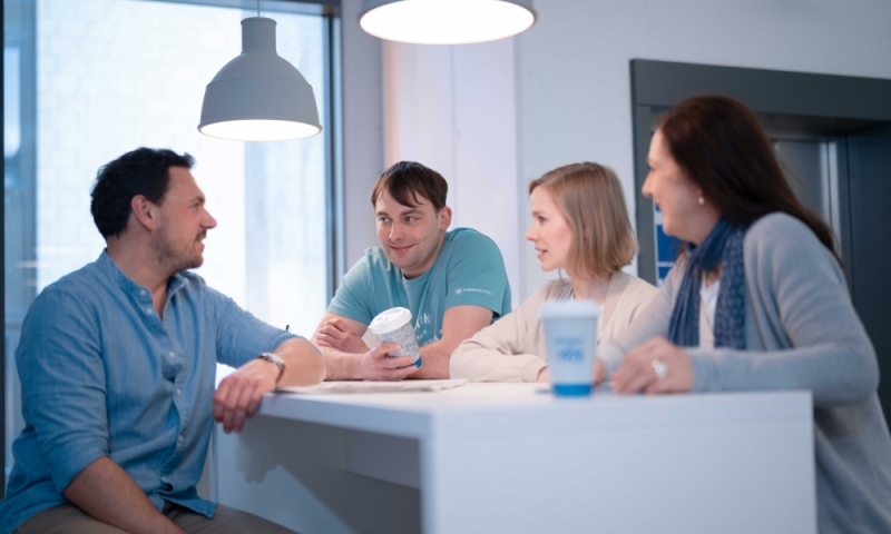 Vier Studierende am Stehpult im lockeren Austausch