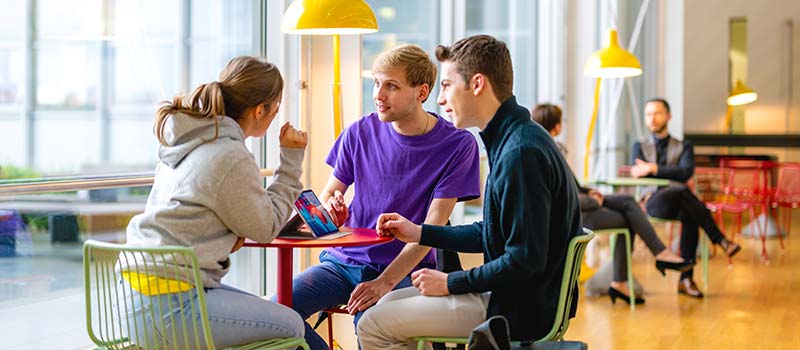 Drei FernUni Erstsemester Studierende sitzen an einem Tisch und unterhalten sich