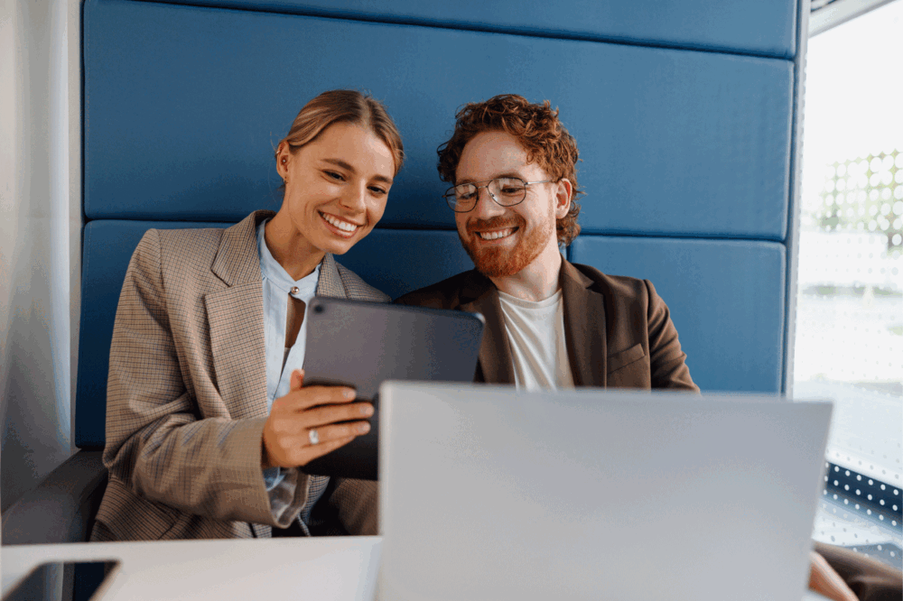 Two enthusiastic young professionals are collaborating on a tablet together in a stylish and modern workspace