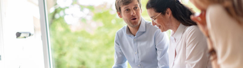 Drei Studentinnen sitzen auf der Wiese vor der Mensa mit einem aufgeklappten Laptop auf der Decke.