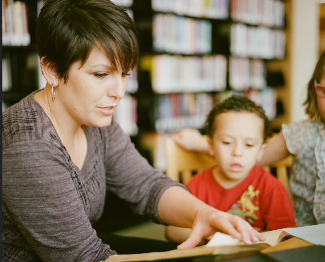 Frau liest Kindern in einer Bibliothek vor