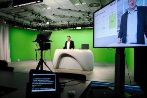 Blick ins ZLI-Studio mit Kamera/Teleprompter, Greenscreen Hintergrund und Videoresultat auf Monitor