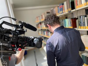 Eine Person in der Bibliothel wird über die Schulter hinweg gefilmt