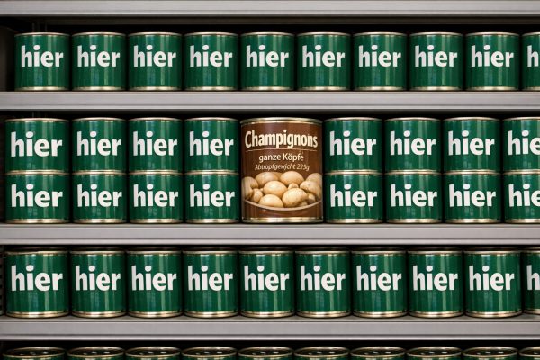 Mehrere Dosen mit der Aufschrift "hier" und eine Dose mit der Aufschrift "Champignons, ganze Köpfe, Abtropfgewicht 225g"
