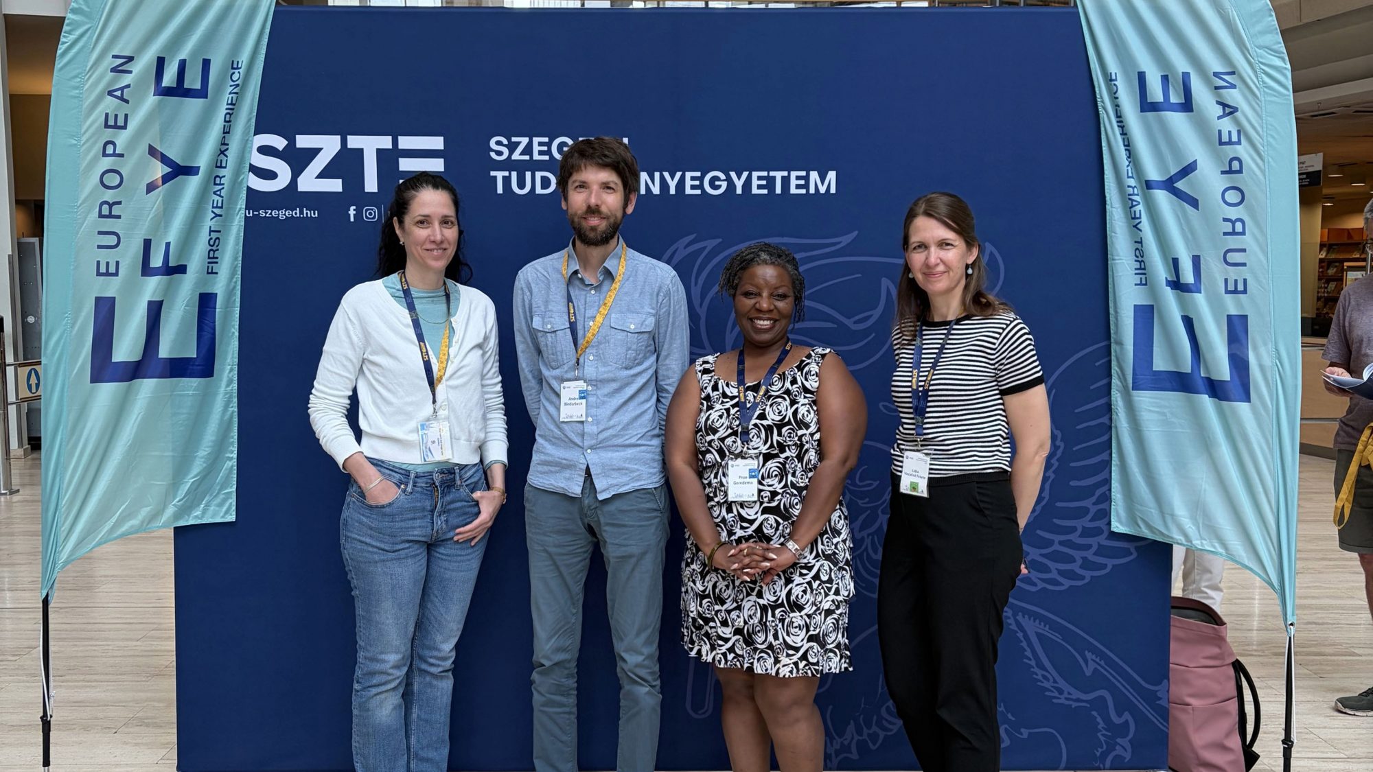 Foto von Réka Futász, Dr André Biedebeck, Dr Prue Goredema und Lídia Vinczéné Fekete vor einem Display der Tagung "European First Year Experience"